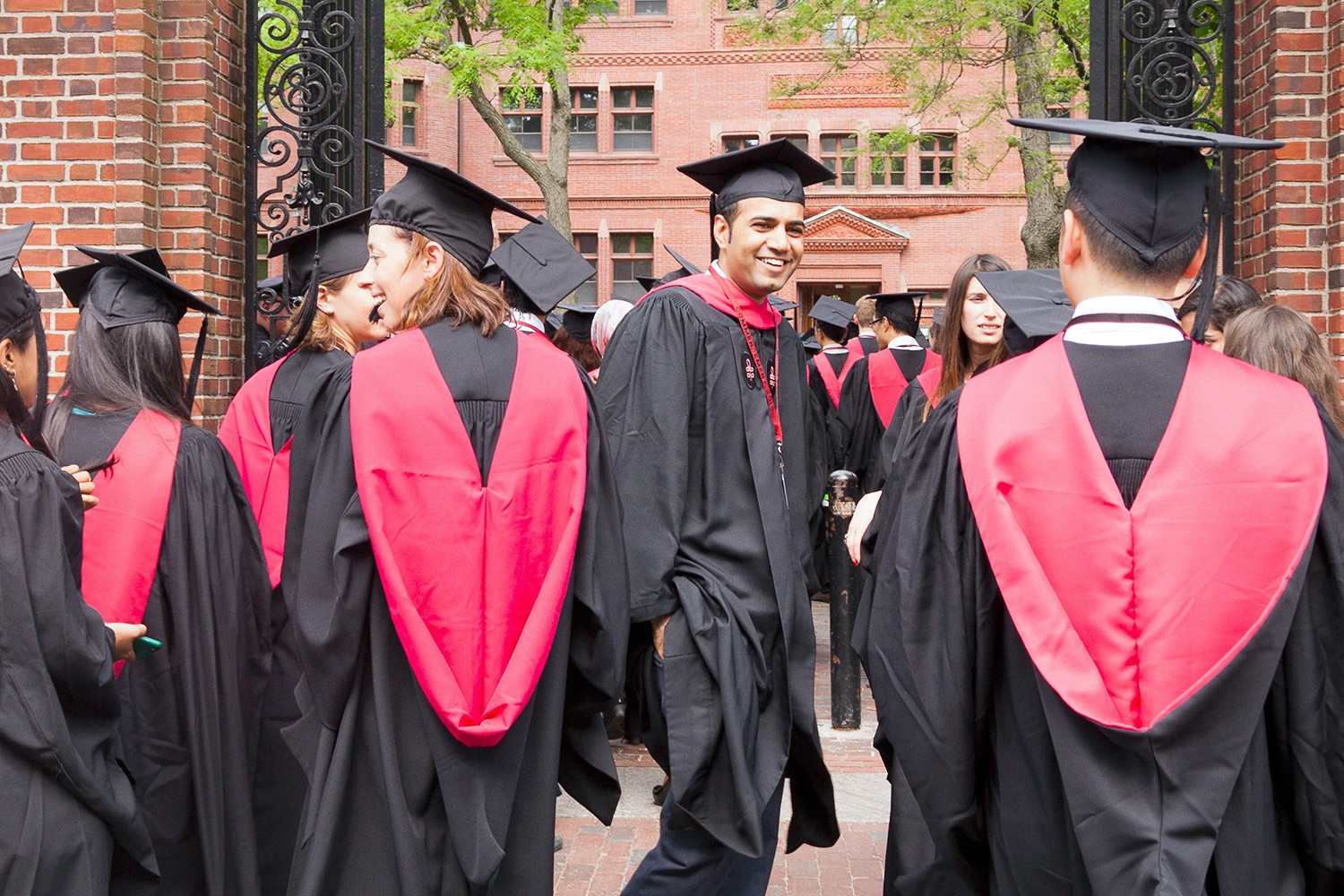 Group of students smiling wearing red Academic Hood